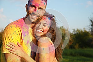 Happy couple covered with colorful powder dyes outdoors. Holi festival celebration