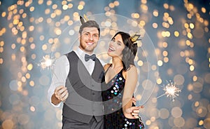 Happy couple with crowns and sparklers at party