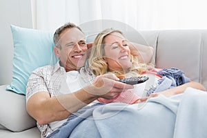 Happy couple cuddling on the couch watching television photo