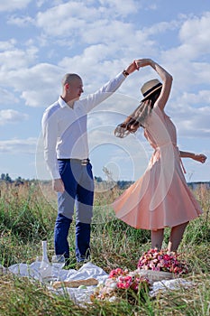 Happy couple dancing in the field. brunette in cream dress and bald man in white shirt and blue pants. love story. husband and