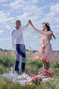 Happy couple dancing in the field. brunette in cream dress and bald man in white shirt and blue pants. love story. husband and