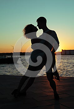 Happy couple dancing tango at sunset on the beach