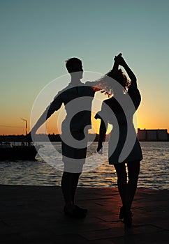 Happy couple dancing tango at sunset on the beach