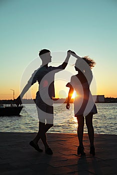 Happy couple dancing tango at sunset on the beach