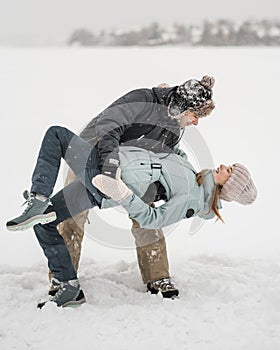 Happy couple dancing together in snow in winer