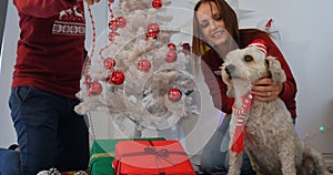 Happy couple with dog sitting near Christmas tree