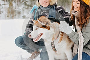 The happy couple with dog haski at the forest nature park in cold season. Travel adventure love story