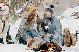 The happy couple with dog haski at the forest nature park in cold season. Travel adventure love story
