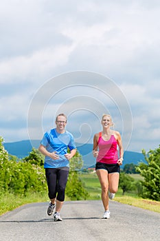 Happy couple doing sport jogging on rural street