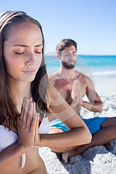 Happy couple doing yoga beside the water