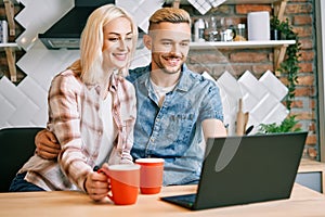 Happy couple drink coffee and using laptop relax together at their kitchen