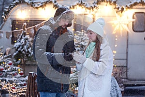 Happy couple drink hot chocolate outdoors, closeup. Woman with man holding cups of tea in hand`s gloves, loving family, Romantic