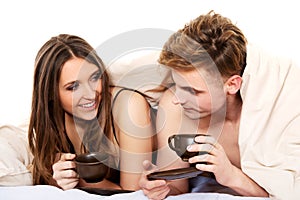 Happy couple drinking coffee in bed.