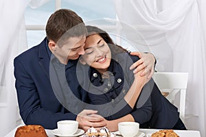 Happy couple drinking coffee and talking near window with a sky view - travel and love concept