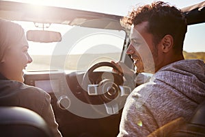 Happy couple driving in car with sunroof open, passenger POV photo