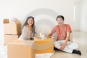 Happy couple eat noodle on carboard box at new house