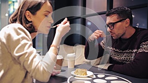 Happy couple eating cake for dessert at cafe