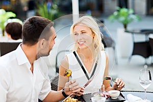 Happy couple eating dinner at restaurant terrace