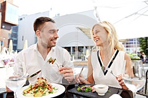 Happy couple eating dinner at restaurant terrace