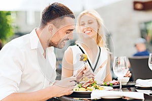 Happy couple eating dinner at restaurant terrace