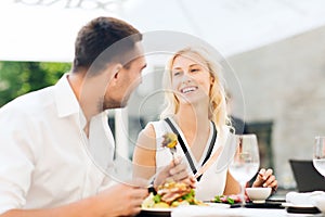 Happy couple eating dinner at restaurant terrace