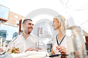 Happy couple eating dinner at restaurant terrace