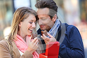 Happy couple eating pastries in town