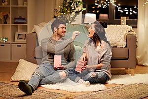 Happy couple eating popcorn at home