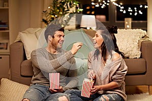 Happy couple eating popcorn at home