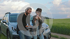 Happy couple eating sandwiches during summer trip by car