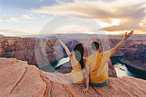 Happy couple on the edge of the cliff at Horseshoe Band Canyon in Paje, Arizona. Adventure and tourism concept