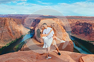 Happy couple on the edge of the cliff at Horseshoe Band Canyon in Paje, Arizona. Adventure and tourism concept