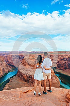 Happy couple on the edge of the cliff at Horseshoe Band Canyon in Paje, Arizona. Adventure and tourism concept