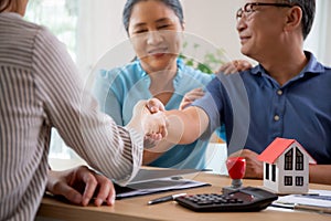 Happy couple elderly handshake with mortgage officer with agreement approve of buying home with loan.