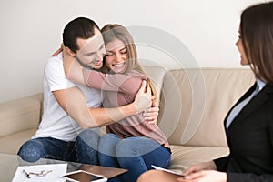 Happy couple embracing buying apartment meeting with real estate