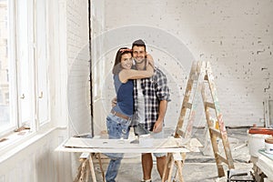 Happy couple embracing in home under construction