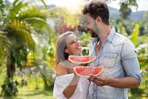 Happy Couple Embracing Looking At Each Other Hold Watermelon Slice Outdoors In Tropical Park Attractive Man and Woman