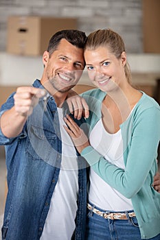 happy couple embracing while man showing key from new flat