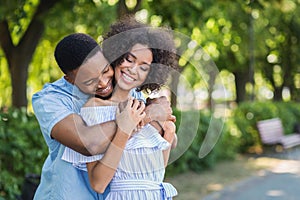 Happy couple embracing in park on sunny day