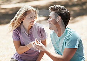 Happy couple, engagement and ring in nature for love, support or commitment in forest or outdoor romance. Young man and