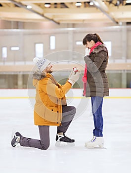 Happy couple with engagement ring on skating rink