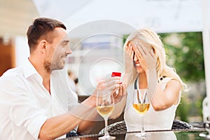 Happy couple with engagement ring and wine at cafe
