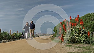 Happy couple enjoying beautiful day walking holding hands on the beach. Close to pacific surf liner rails travel vacation