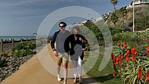 Happy couple enjoying beautiful day walking holding hands on the beach. Close to Pacific surf liner rails travel vacation