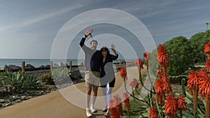 Happy couple enjoying beautiful day walking holding hands on the beach. Close to pacific surf liner rails travel vacation