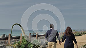 Happy Couple Enjoying Beautiful Day Walking holding hands on the Beach. CLose to Pacific surfliner rails Travel Vacation