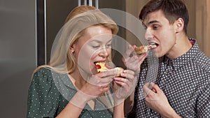 Happy couple enjoying delicious pizza in their new apartment in the kitchen