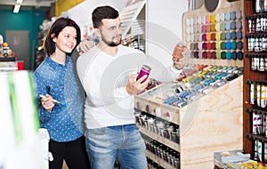 happy couple examining various paints in paint store