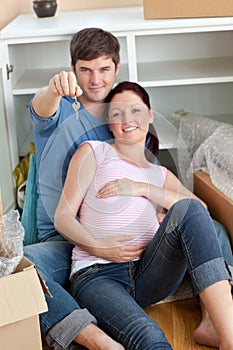 Happy couple expecting a baby sitting on the floor