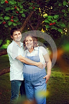 Happy couple expecting a baby walks in summer in a beautiful Par